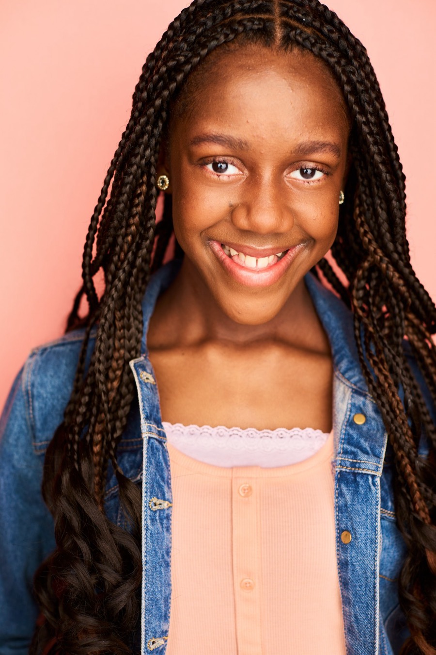 Abby Bernard smiling in a denim jacket against a peach backdrop